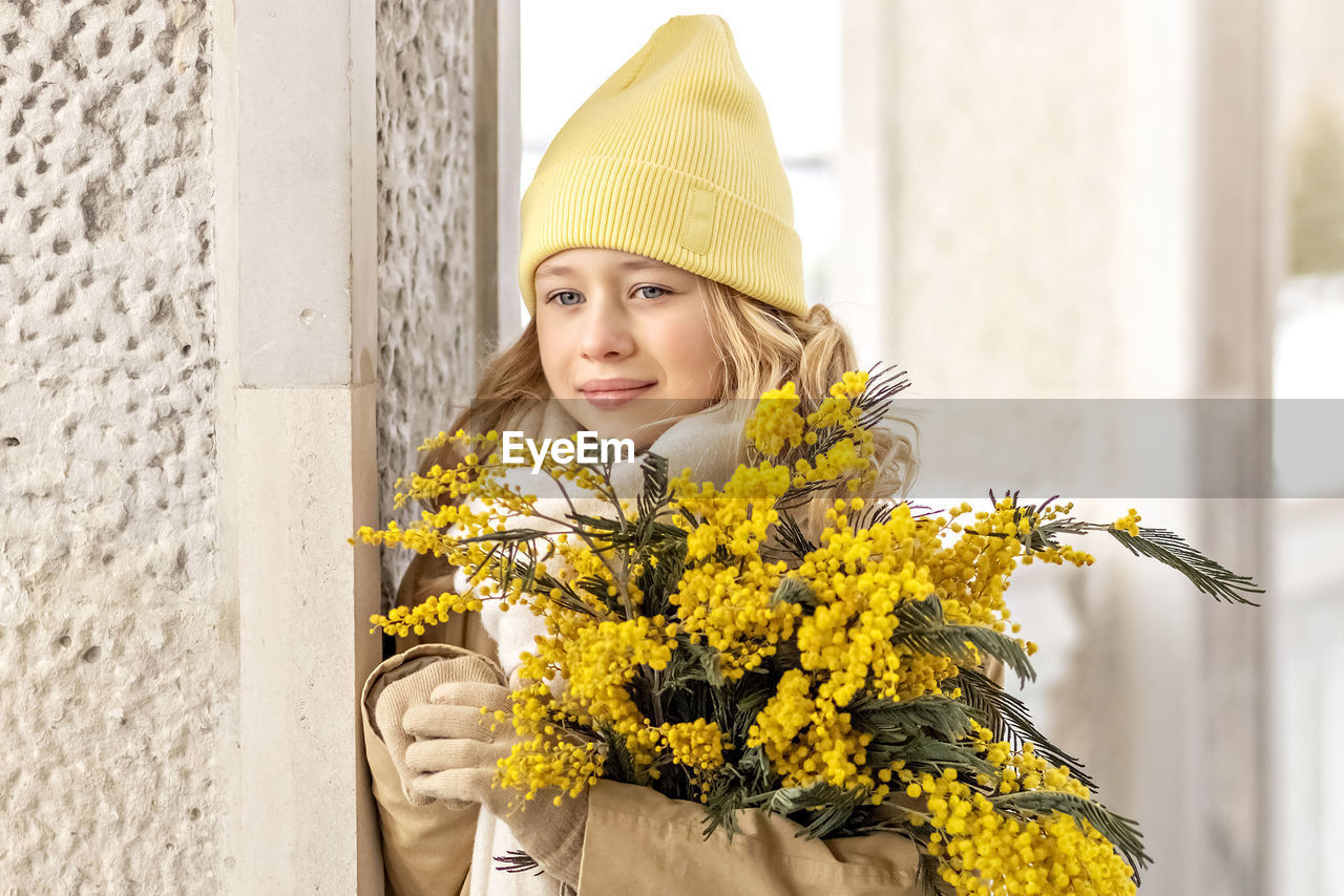 yellow, one person, spring, women, portrait, flowering plant, flower, adult, plant, nature, smiling, happiness, hat, clothing, young adult, emotion, looking at camera, architecture, female, outdoors, lifestyles, headwear, person, day, front view, standing, cheerful, blond hair, looking, beauty in nature, cap, fashion, holding