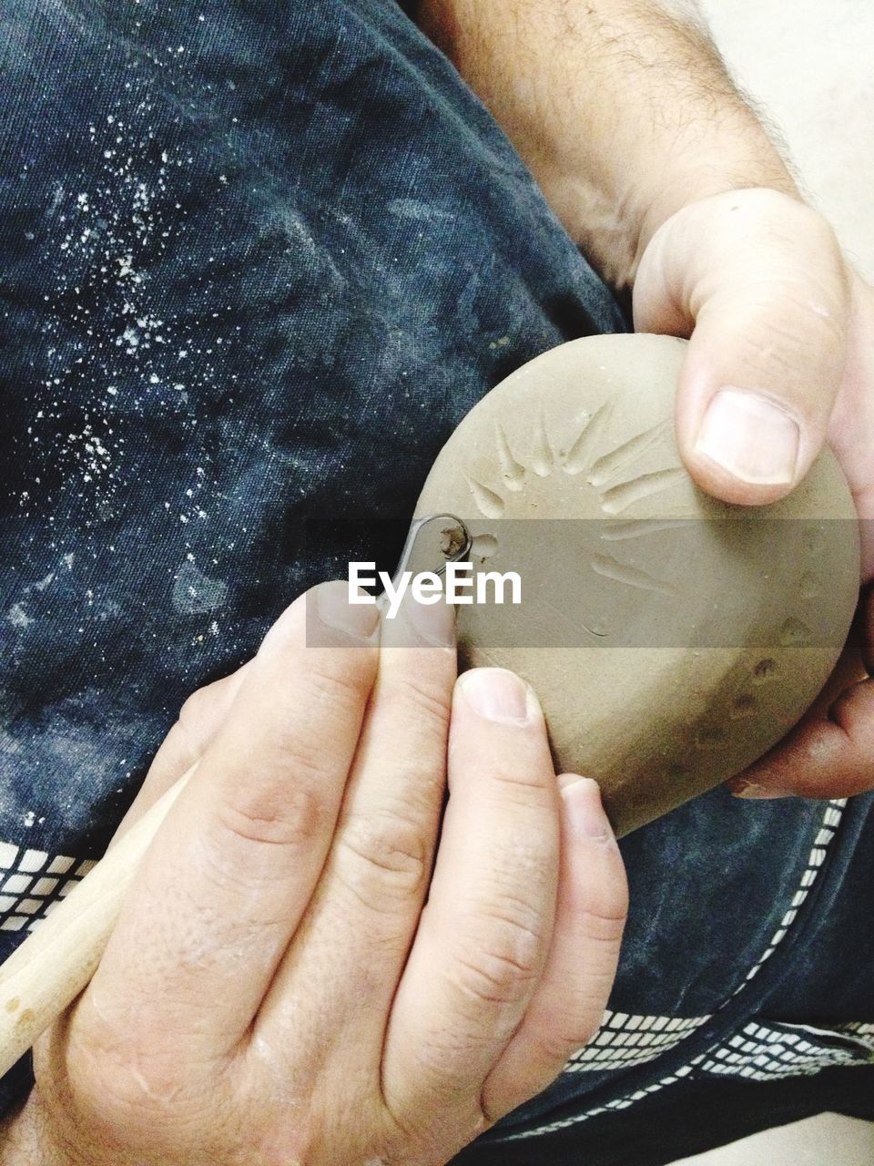 Midsection of person engraving on clay at workshop