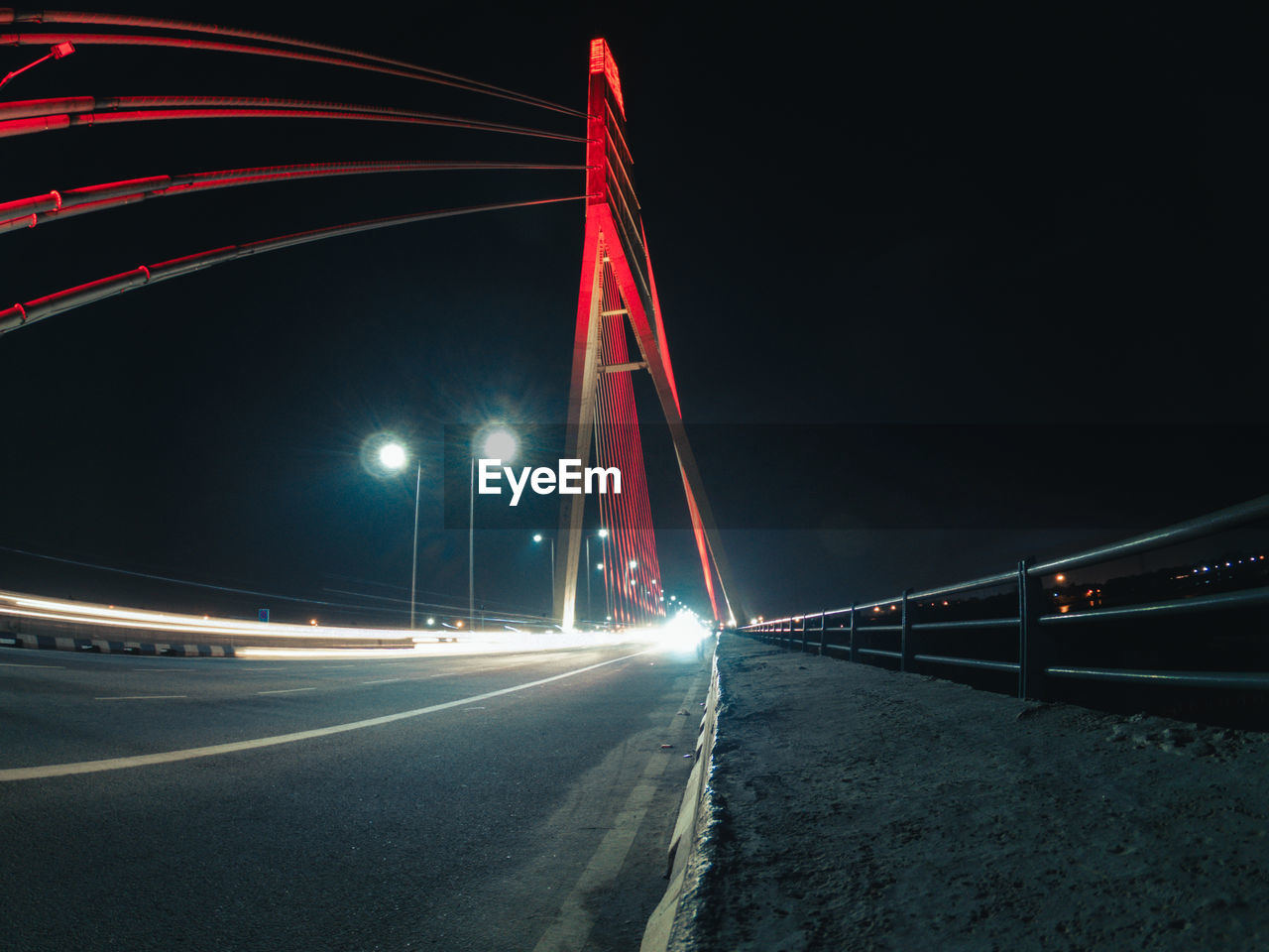 LIGHT TRAILS ON BRIDGE OVER ROAD AT NIGHT