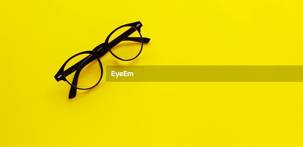 High angle view of eyeglasses against yellow background