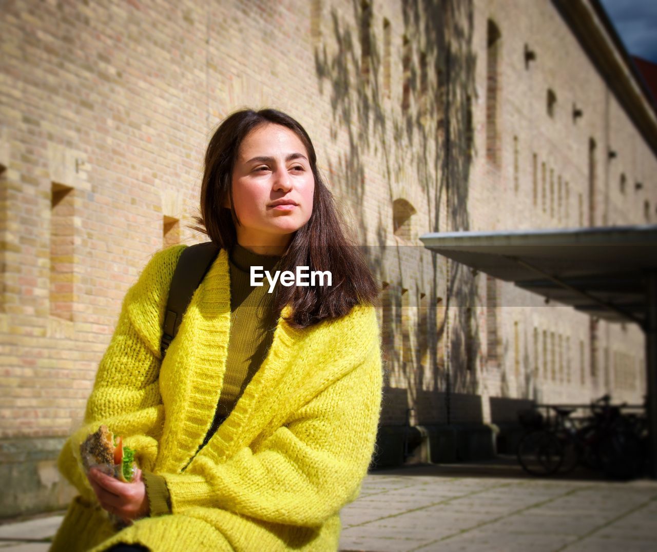 Beautiful woman sitting by building in city