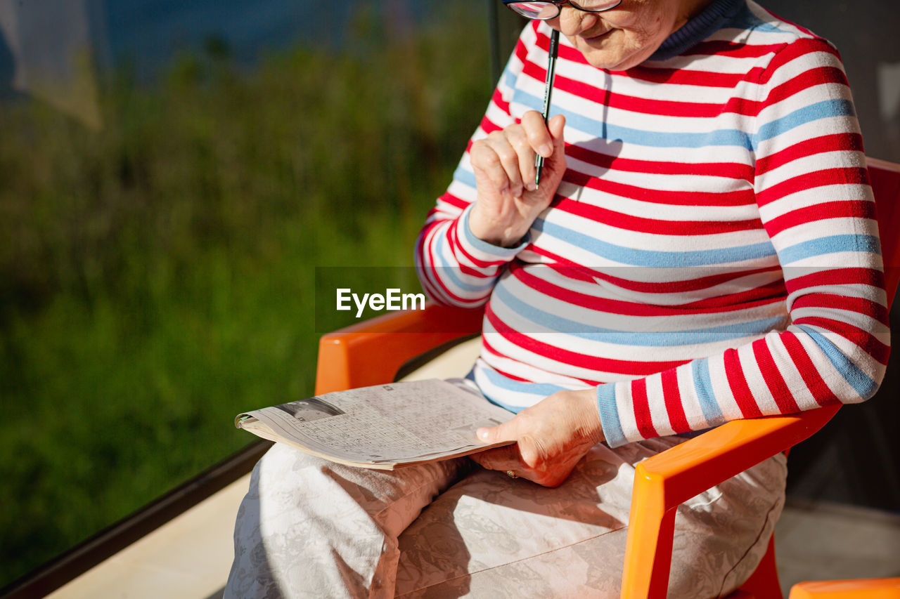 Elderly woman in glasses sitting on balcony near the sea
