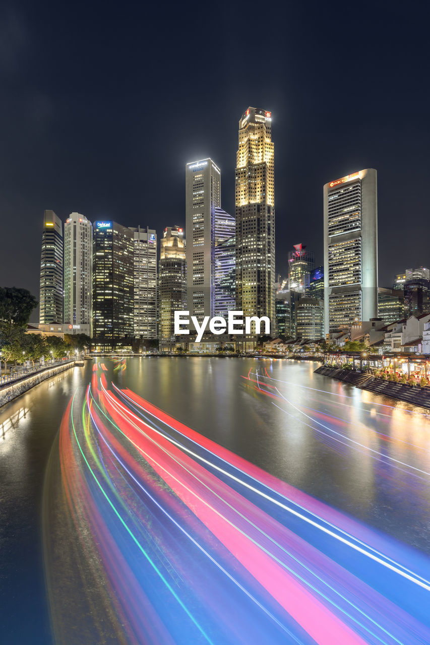 Light trails on illuminated buildings in city at night