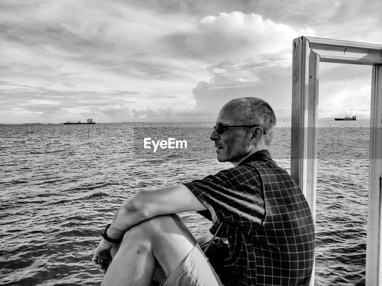 Man sitting in sea against sky