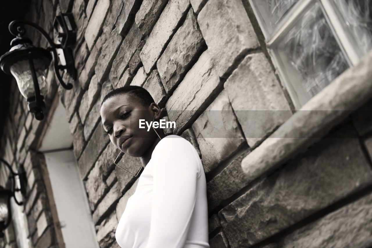 LOW ANGLE VIEW OF YOUNG MAN LOOKING THROUGH WALL