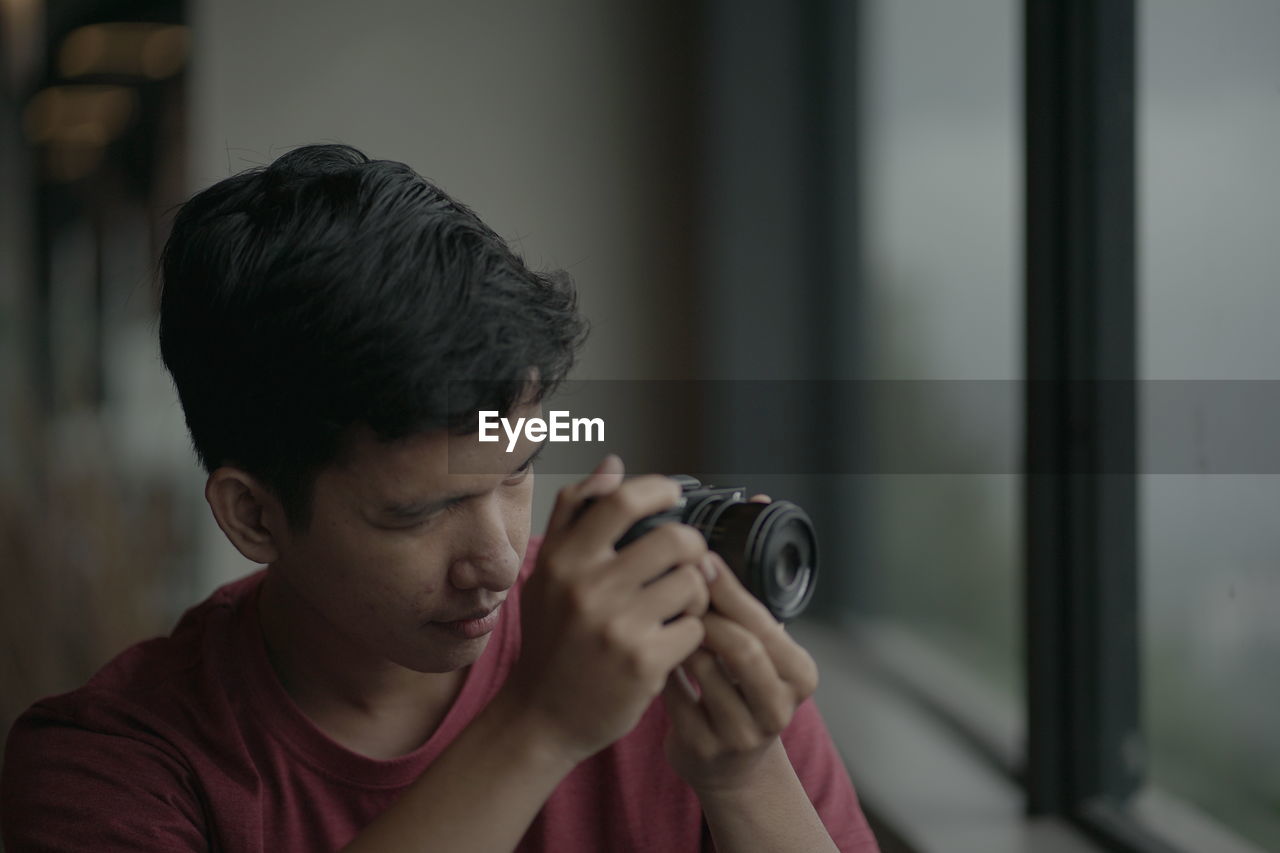 Young man photographing through window