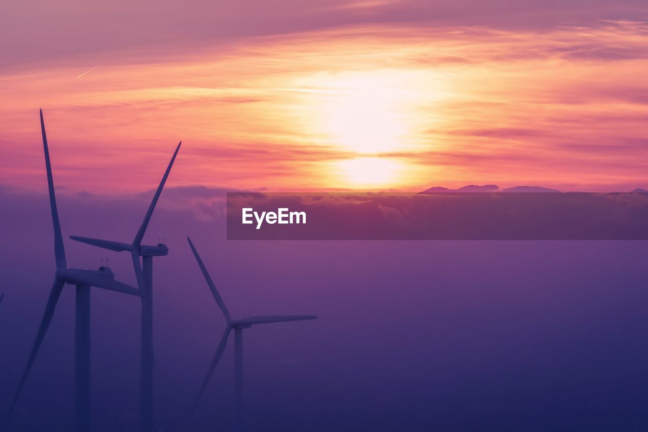 SILHOUETTE OF WINDMILL AGAINST ORANGE SKY