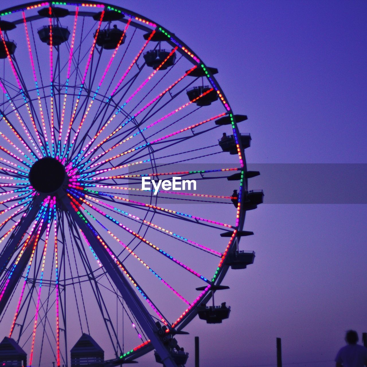 Low angle view of illuminated ferris wheel against clear sky at dusk