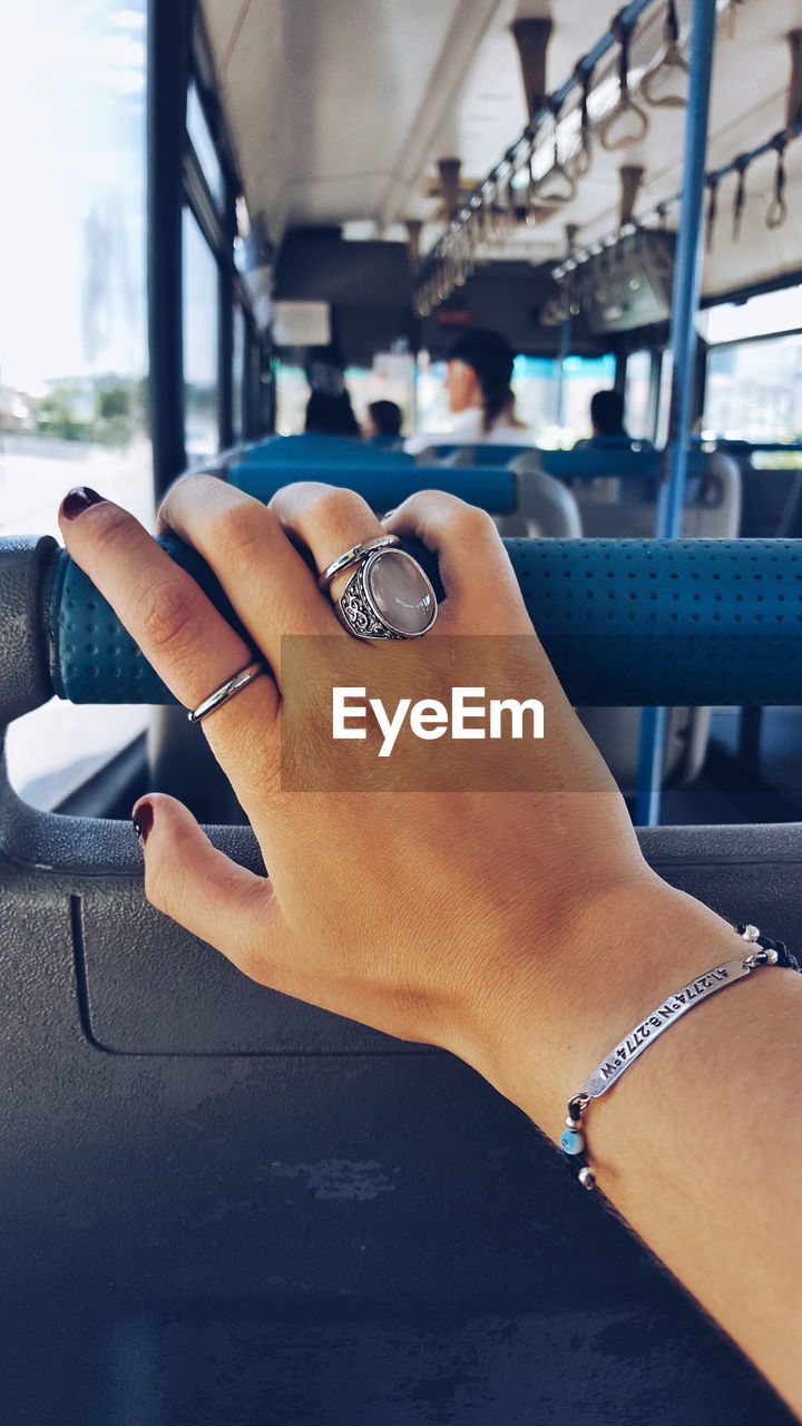 Close-up of woman hand wearing rings touching vehicle seat in bus