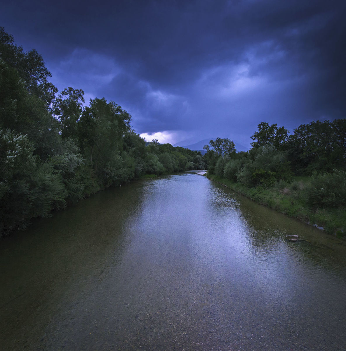 Scenic view of river against cloudy sky