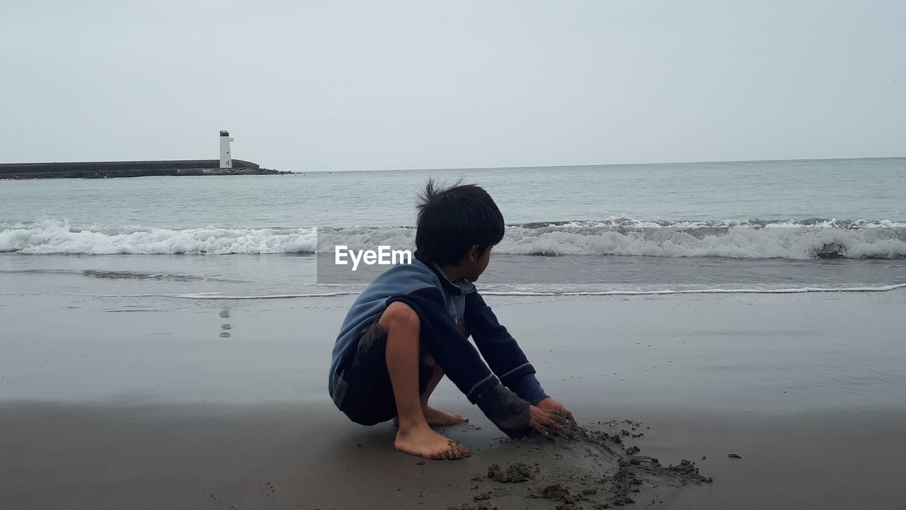 Boy playing with sand at beach