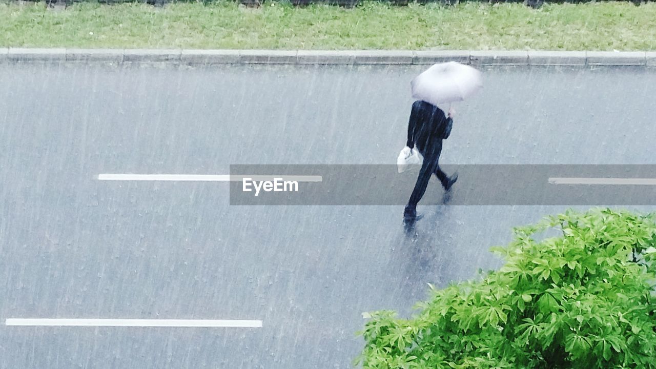 REAR VIEW OF MAN WALKING ON ROAD