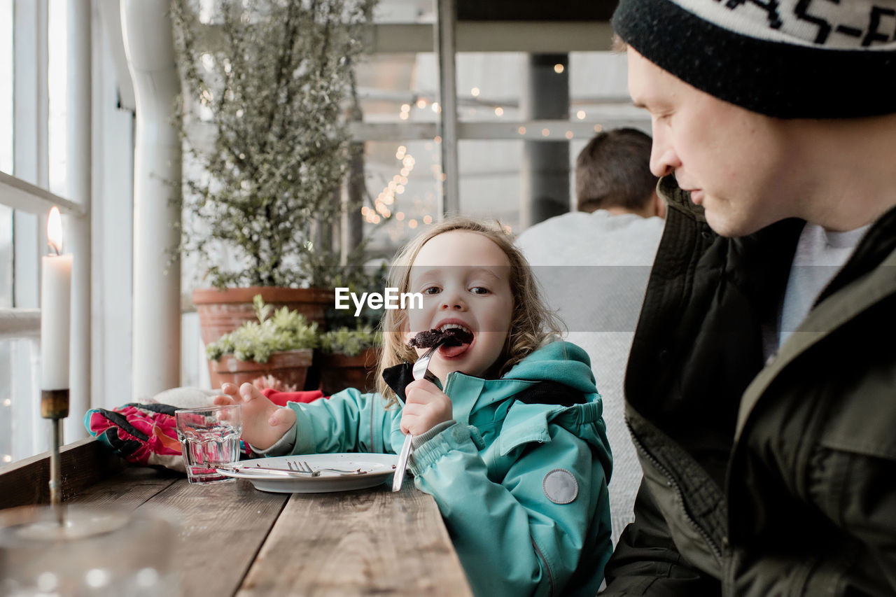 Father and daughter eating chocolate cake in a cafe together