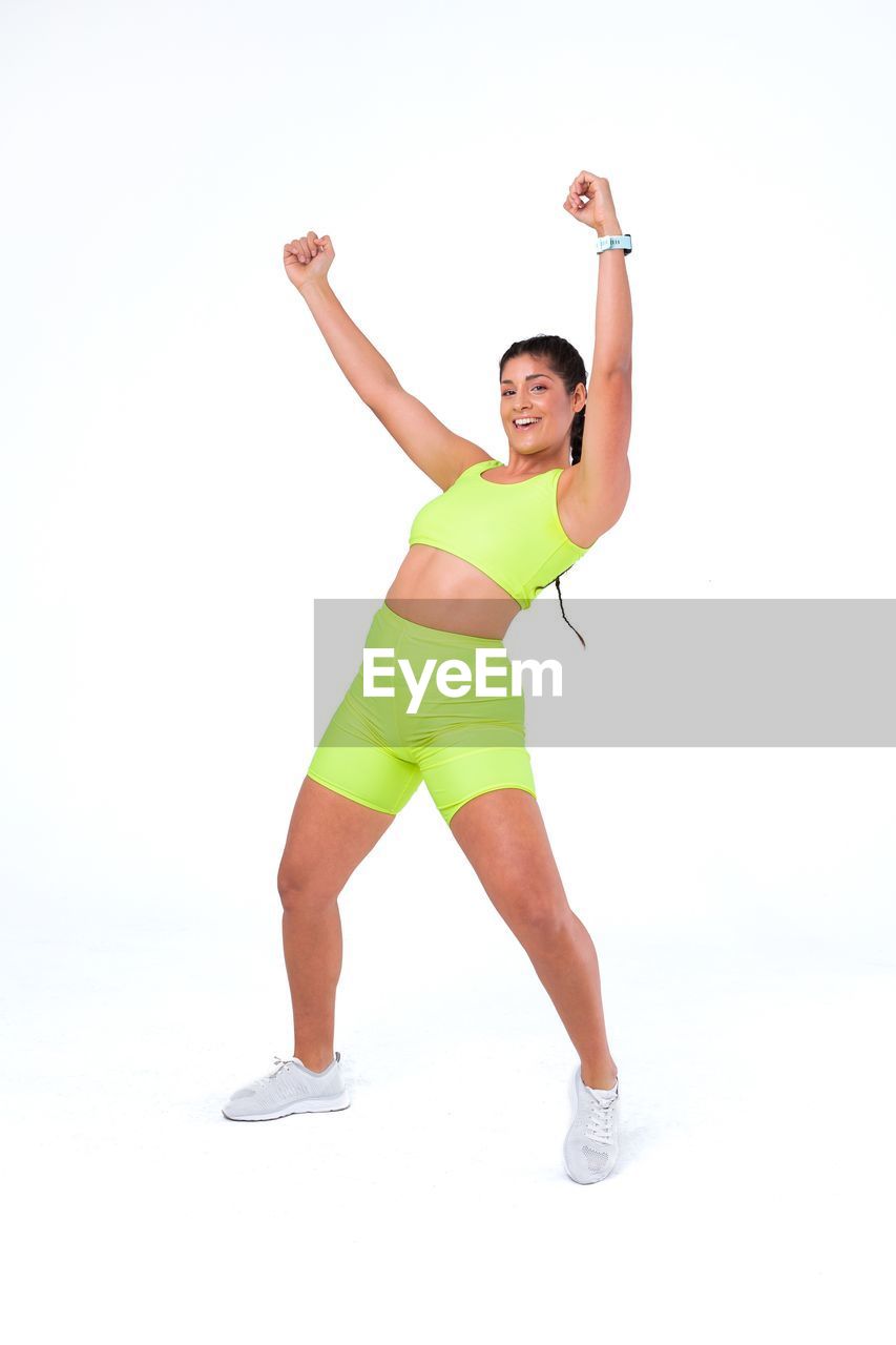 Portrait of young woman dancing against white background