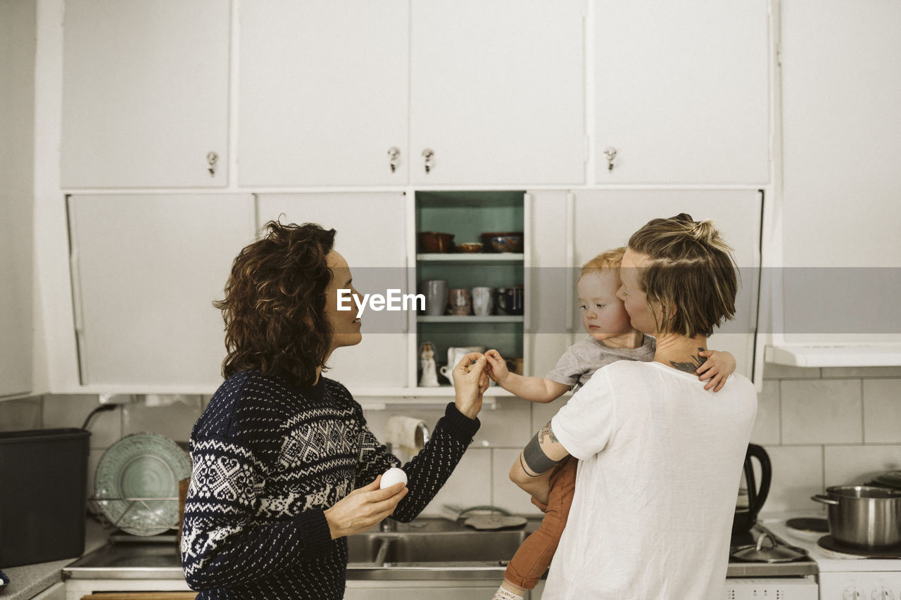 Lesbian mothers with daughter in kitchen at home