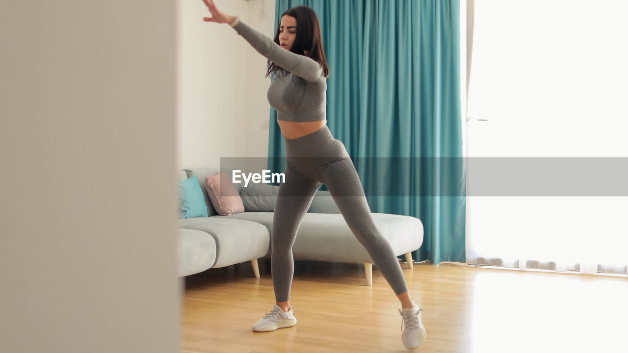 full length of woman doing yoga on hardwood floor