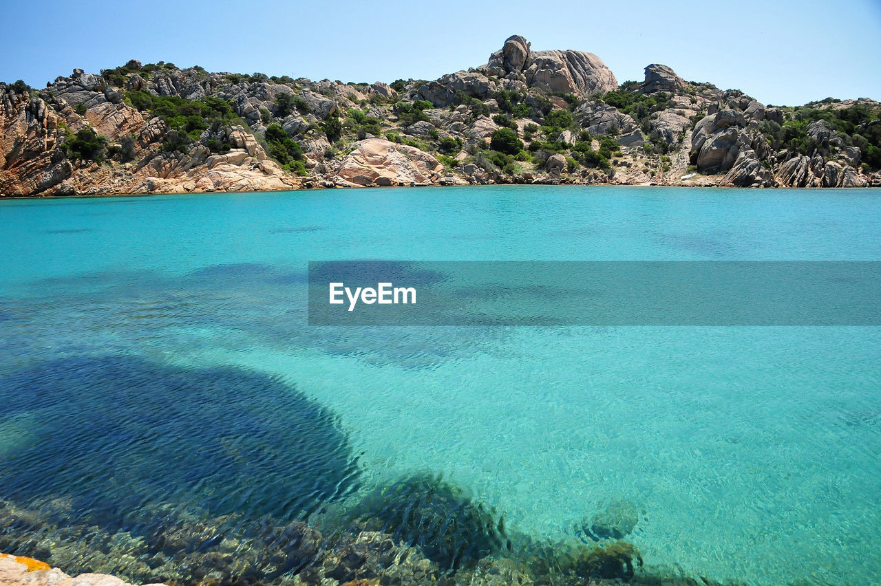 SCENIC VIEW OF SEA AND ROCKS AGAINST CLEAR BLUE SKY