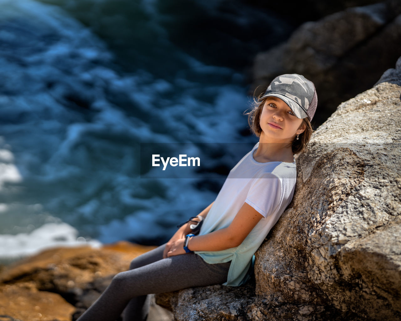 High angle portrait of girl standing by rock by sea