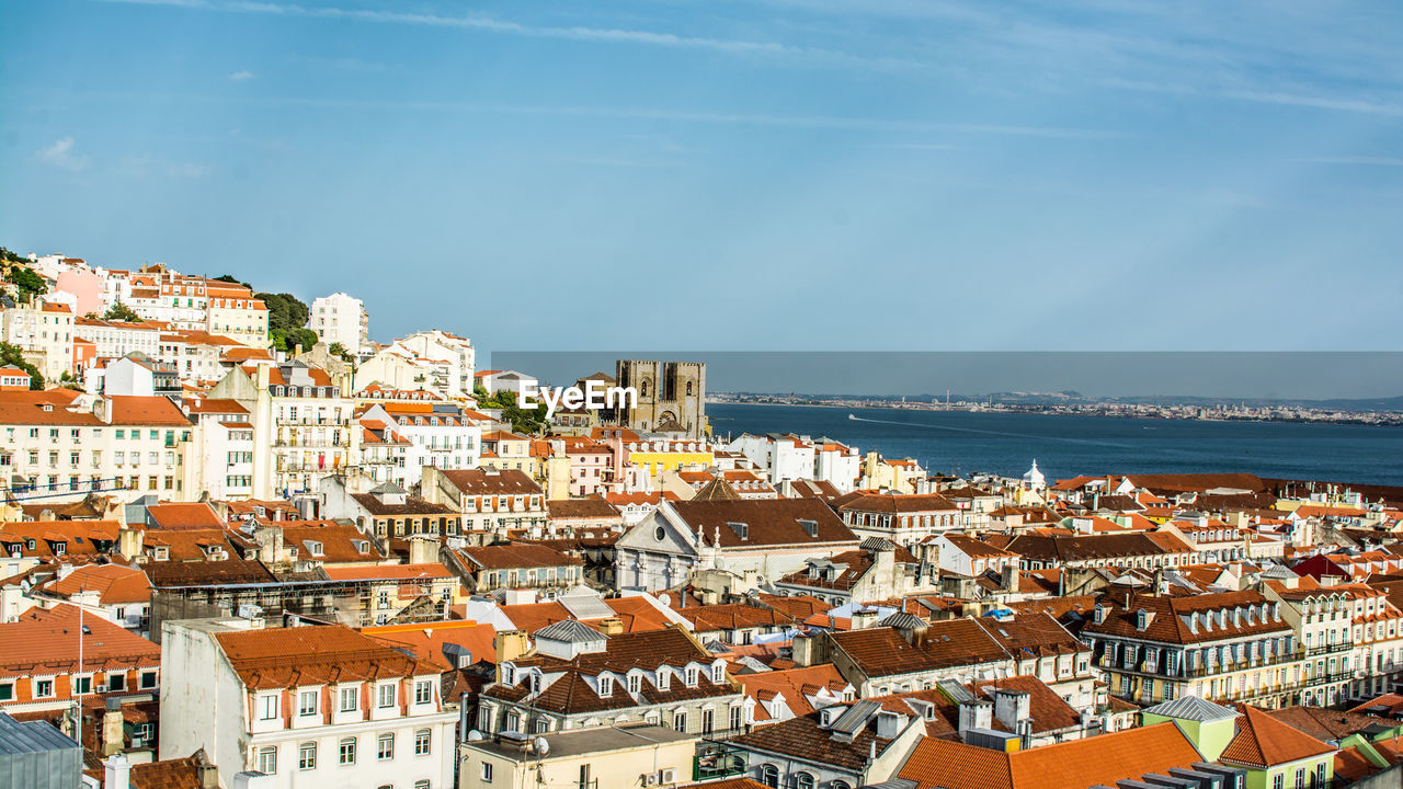 Cityscape by sea against sky