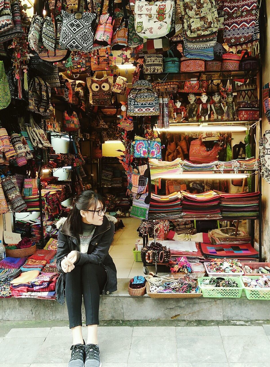 Young woman sitting at merchandise store in market