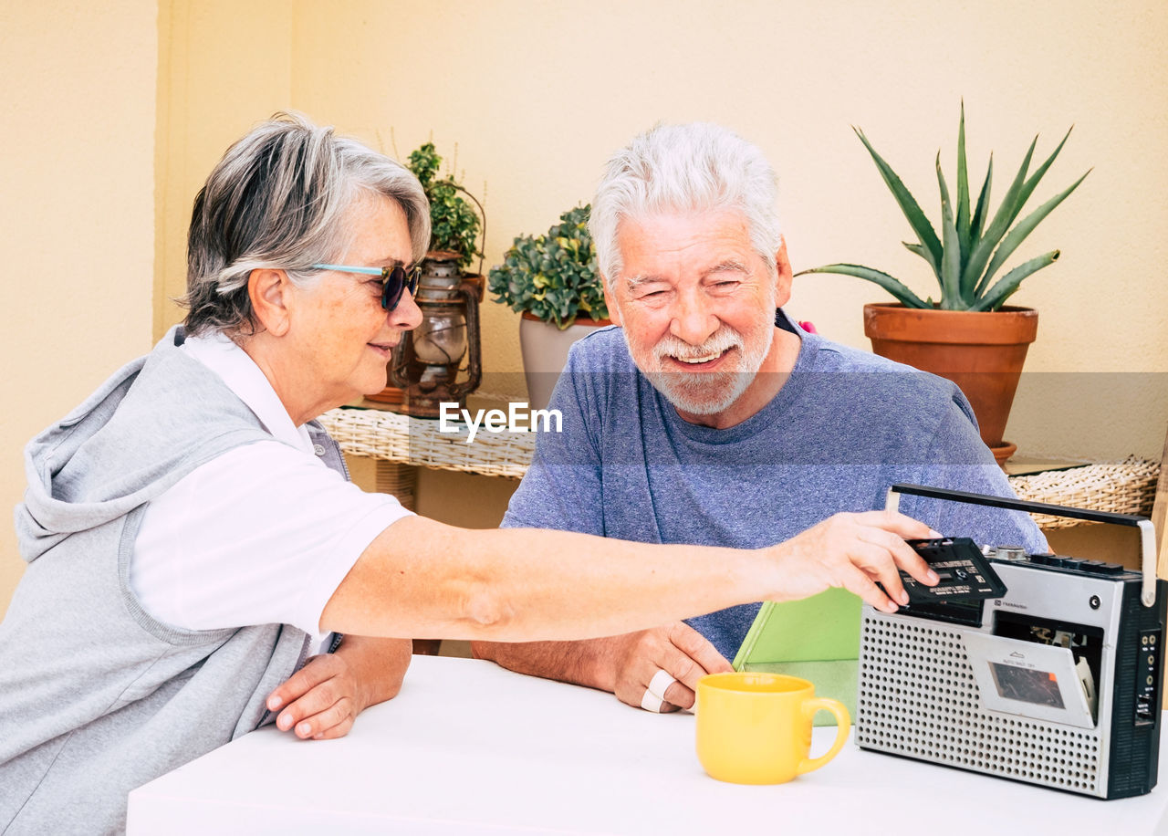 Smiling senior couple using radio on table