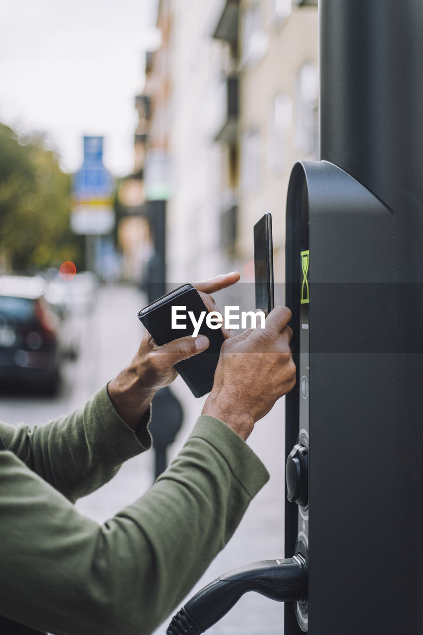 Hands of man doing mobile payment at charging station