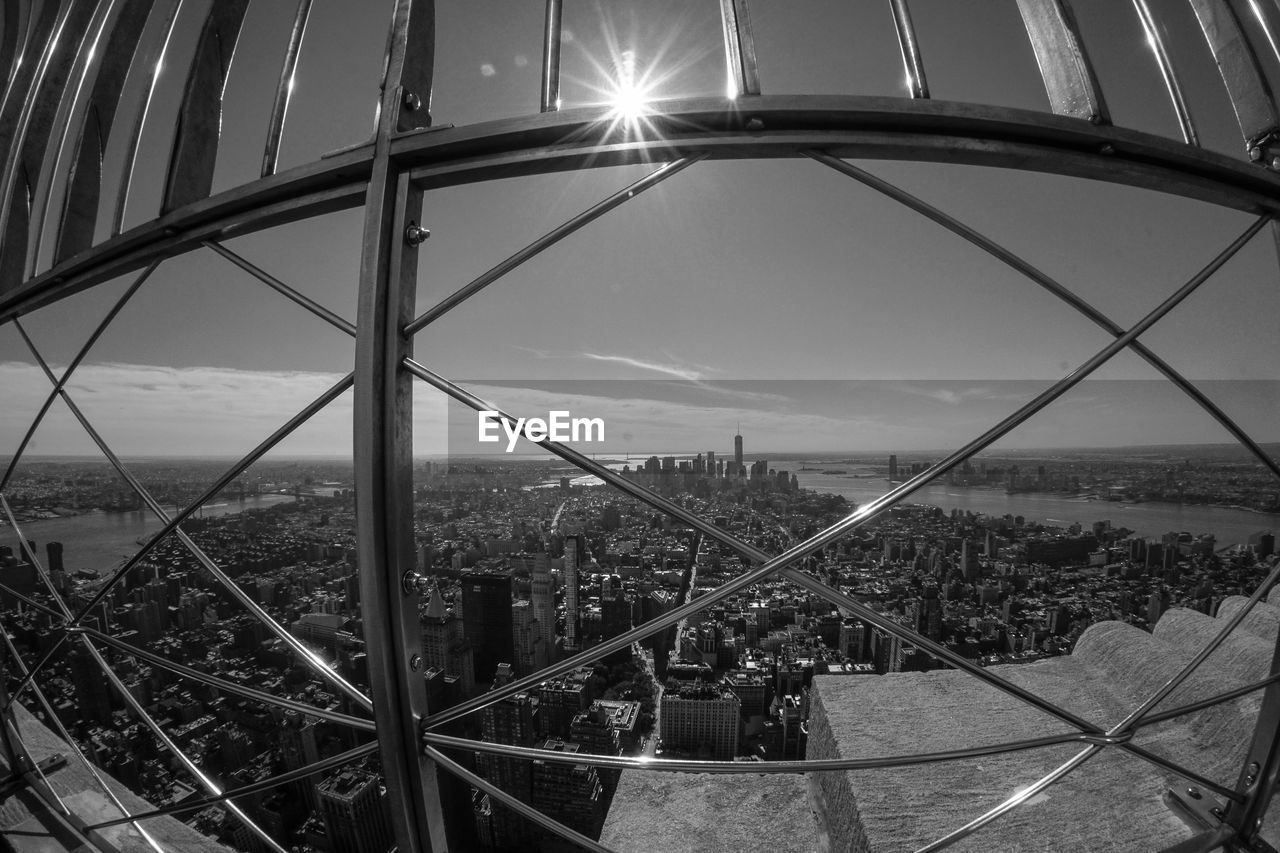 Cityscape against sky seen from metal grate