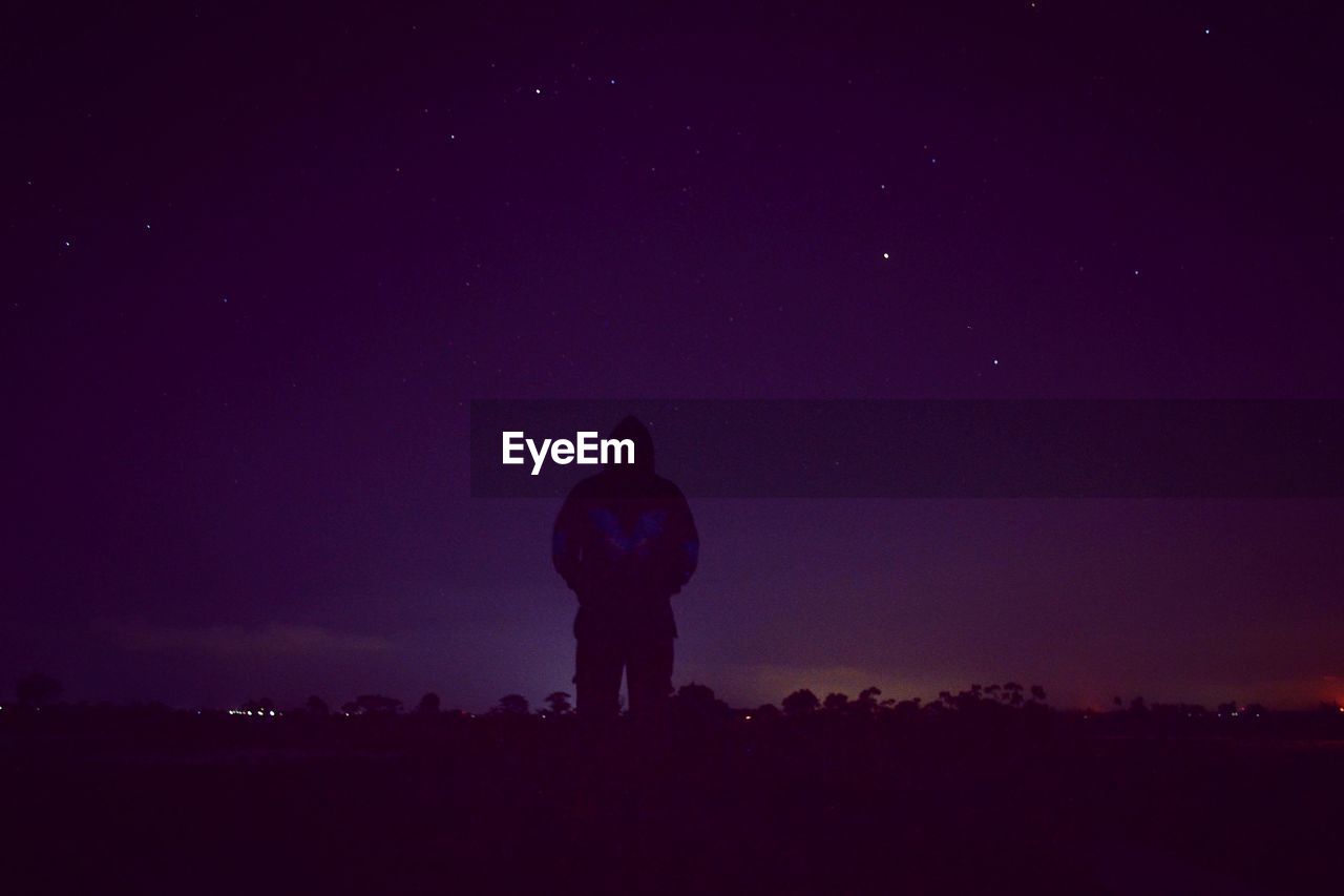 A man standing on field against sky at night