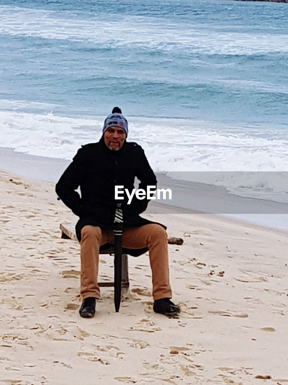 MAN SITTING ON BEACH