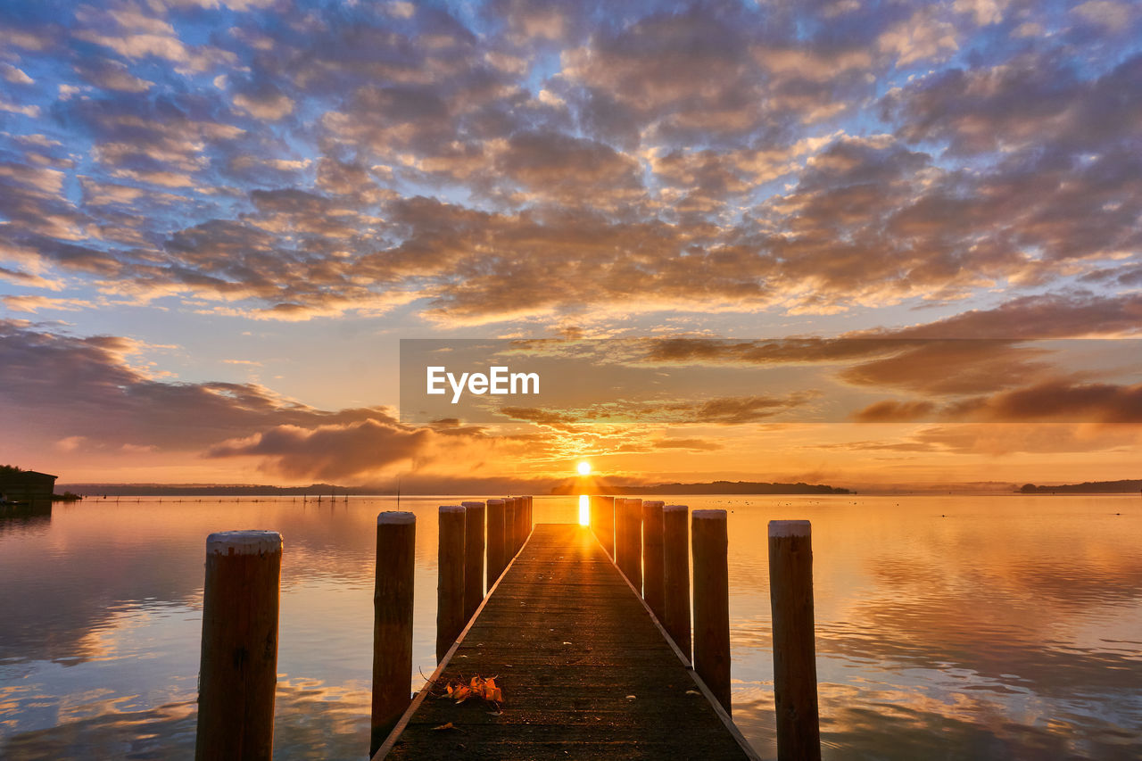 Pier over sea against sky during sunset