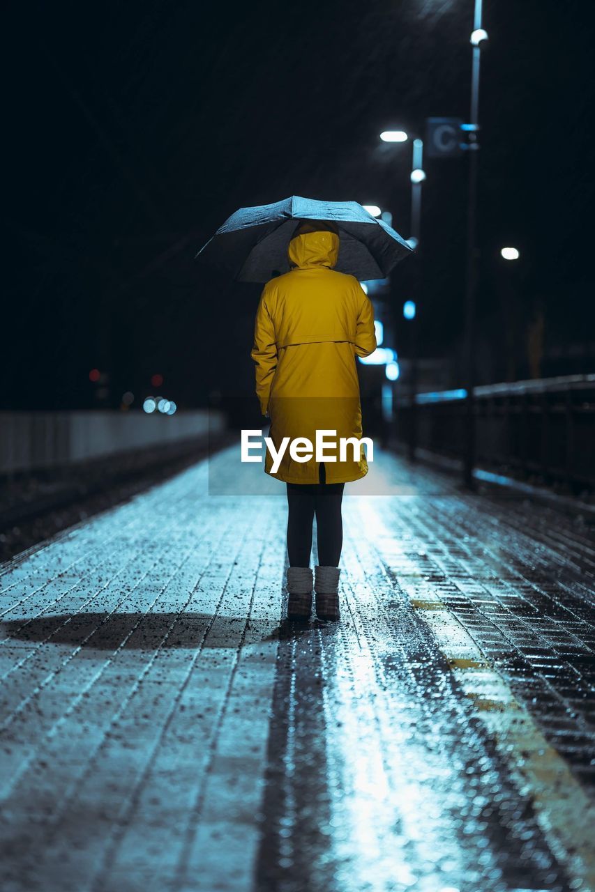 Rear view of woman standing on wet street