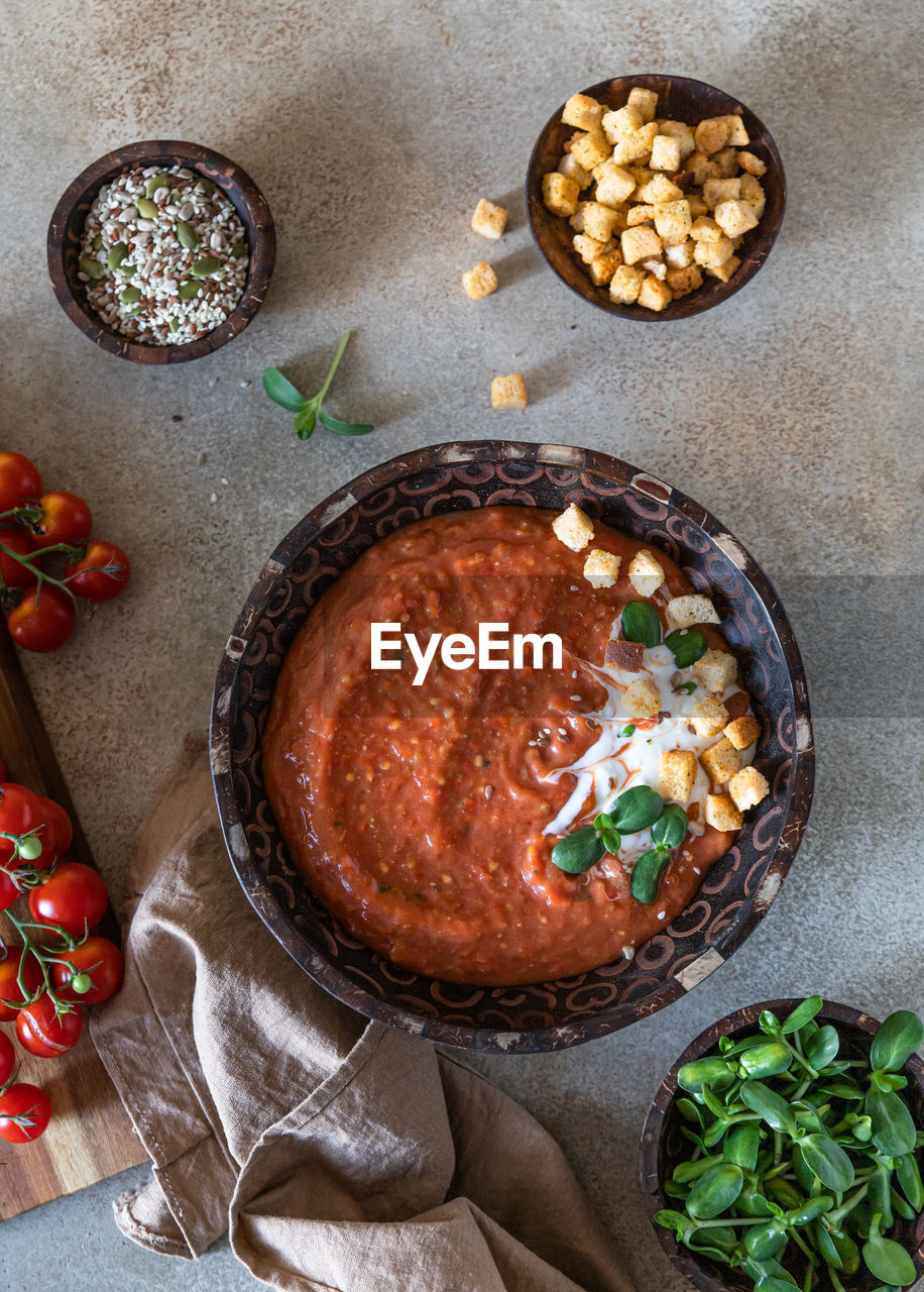 Homemade tomato soup with cream, croutons and microgreen in wooden bowl