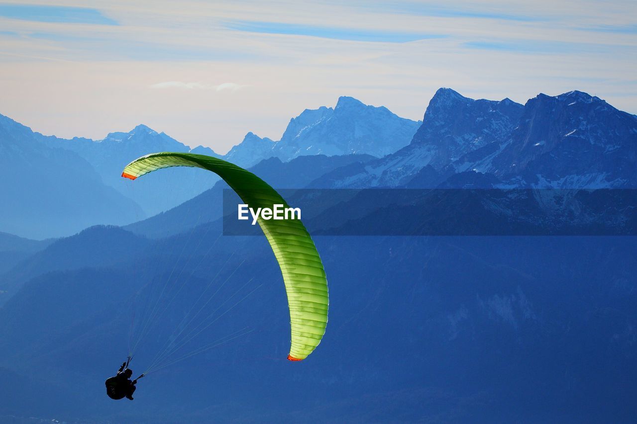 Person paragliding against mountains