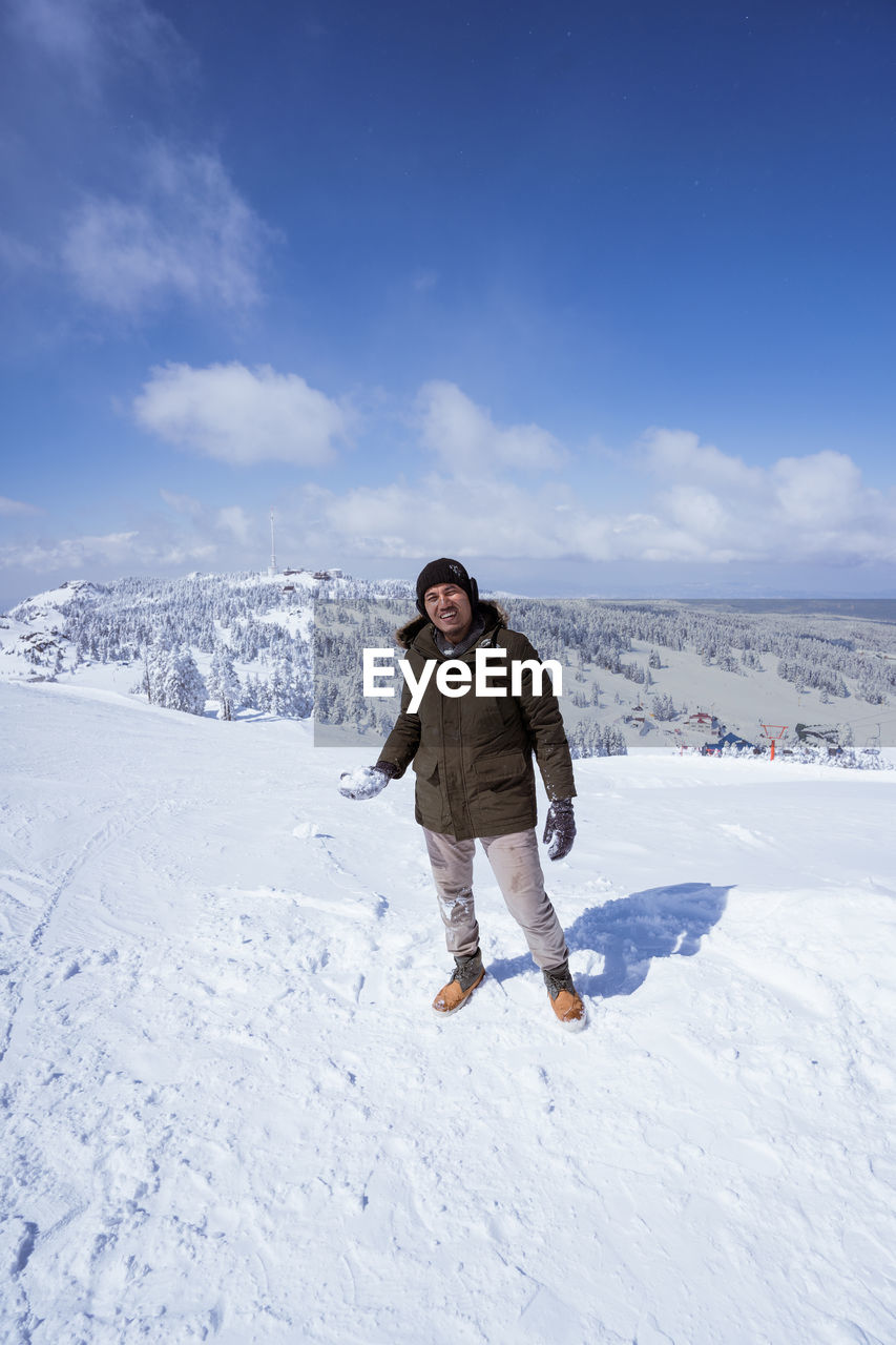 full length of woman standing on snow covered landscape against sky