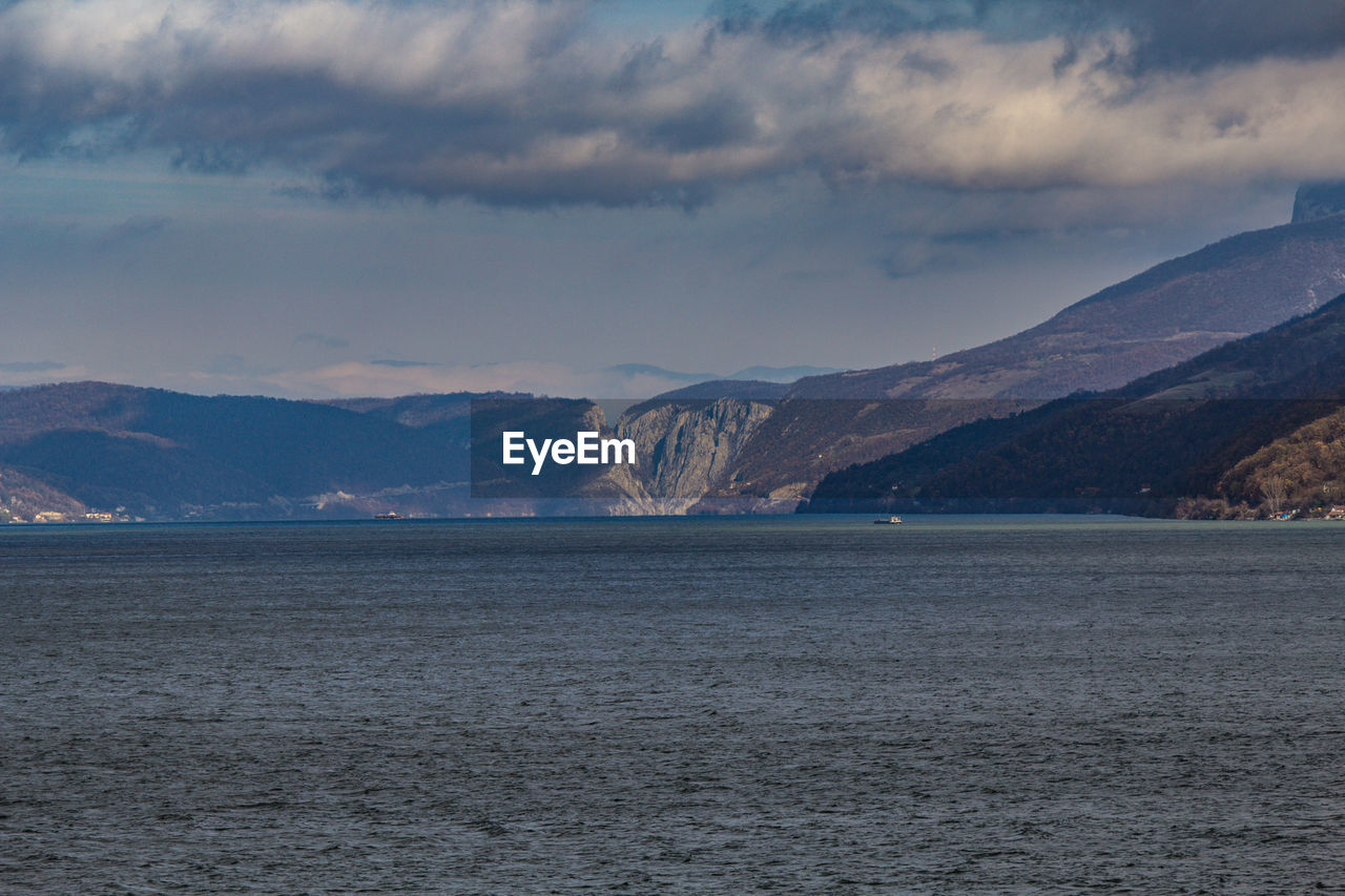 Scenic view of river by mountains against sky