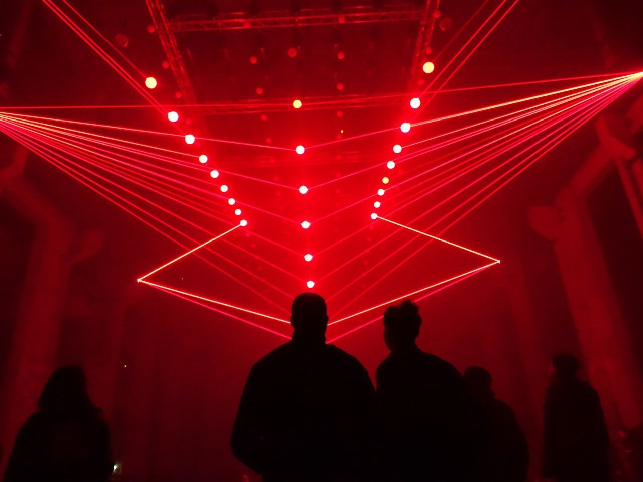 Low angle view of people standing against illuminated laser lights