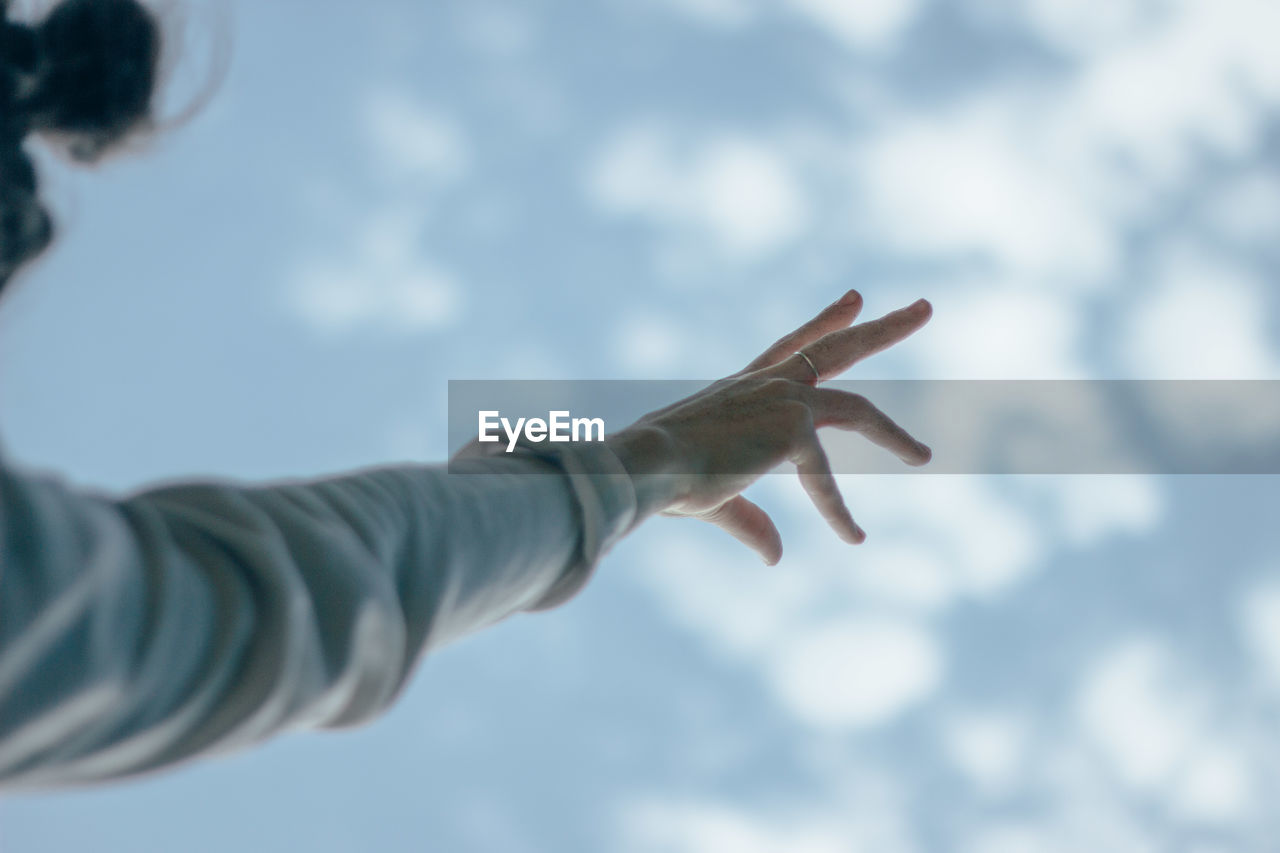 LOW ANGLE VIEW OF HUMAN HAND AGAINST SKY AT DUSK