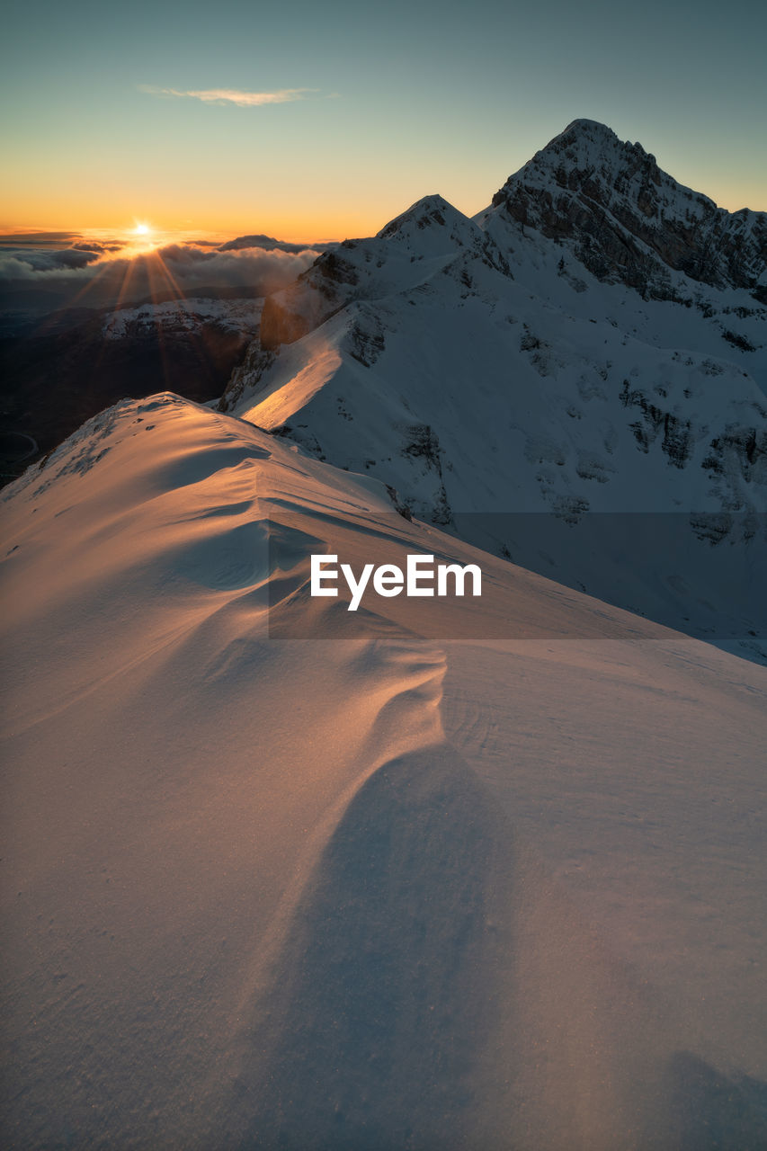 Scenic view of snowcapped mountains against sky during sunset