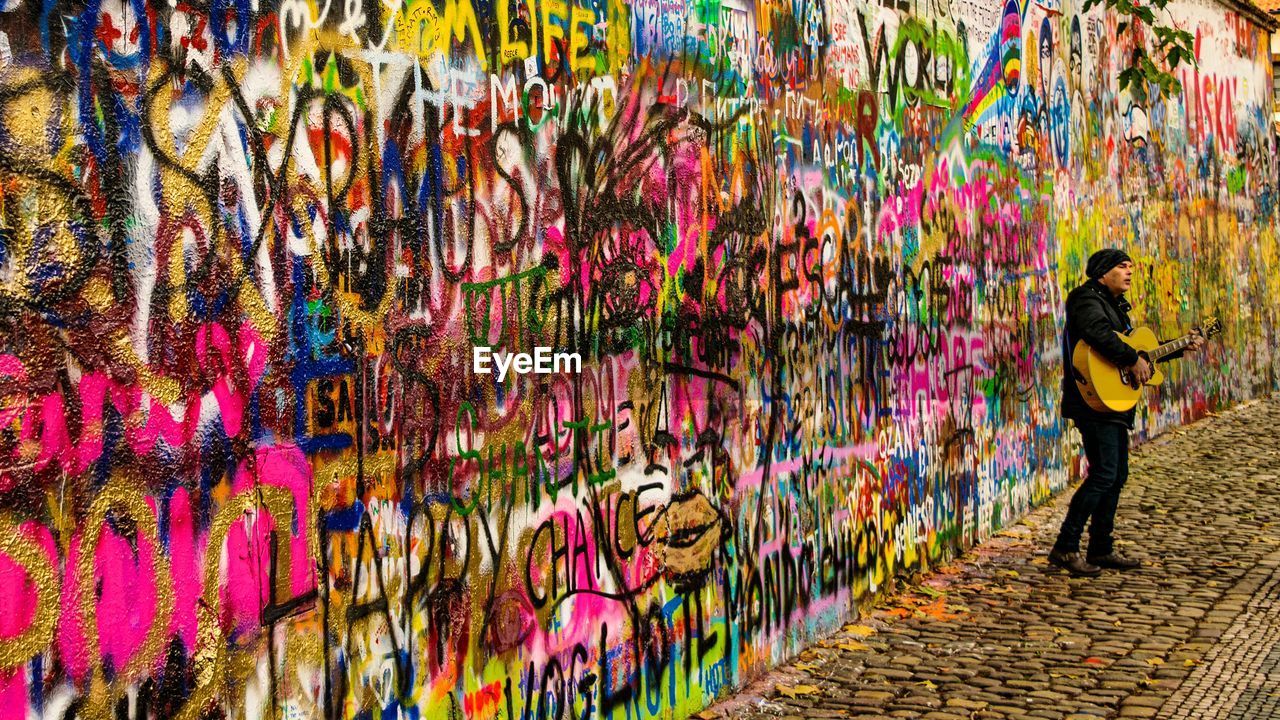 Full length of man standing against graffiti wall