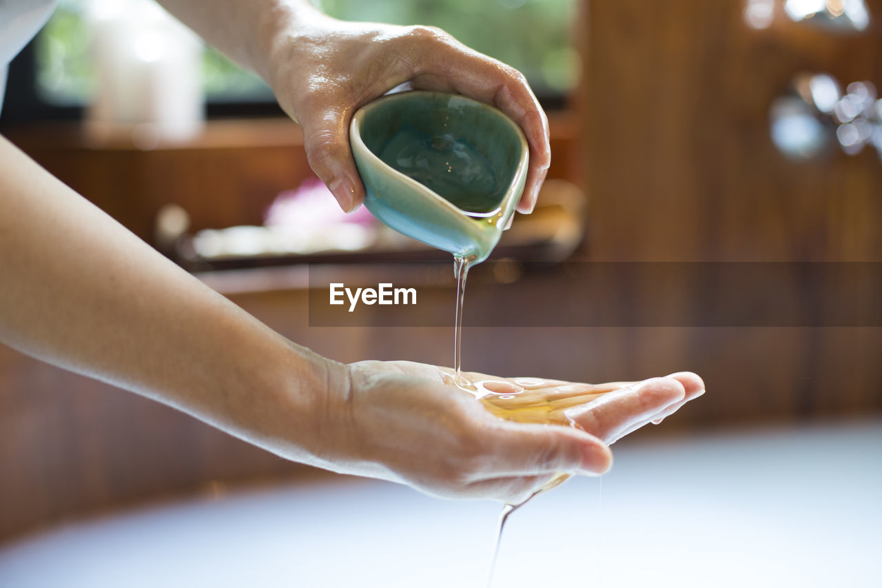 Cropped hand of woman pouring oil