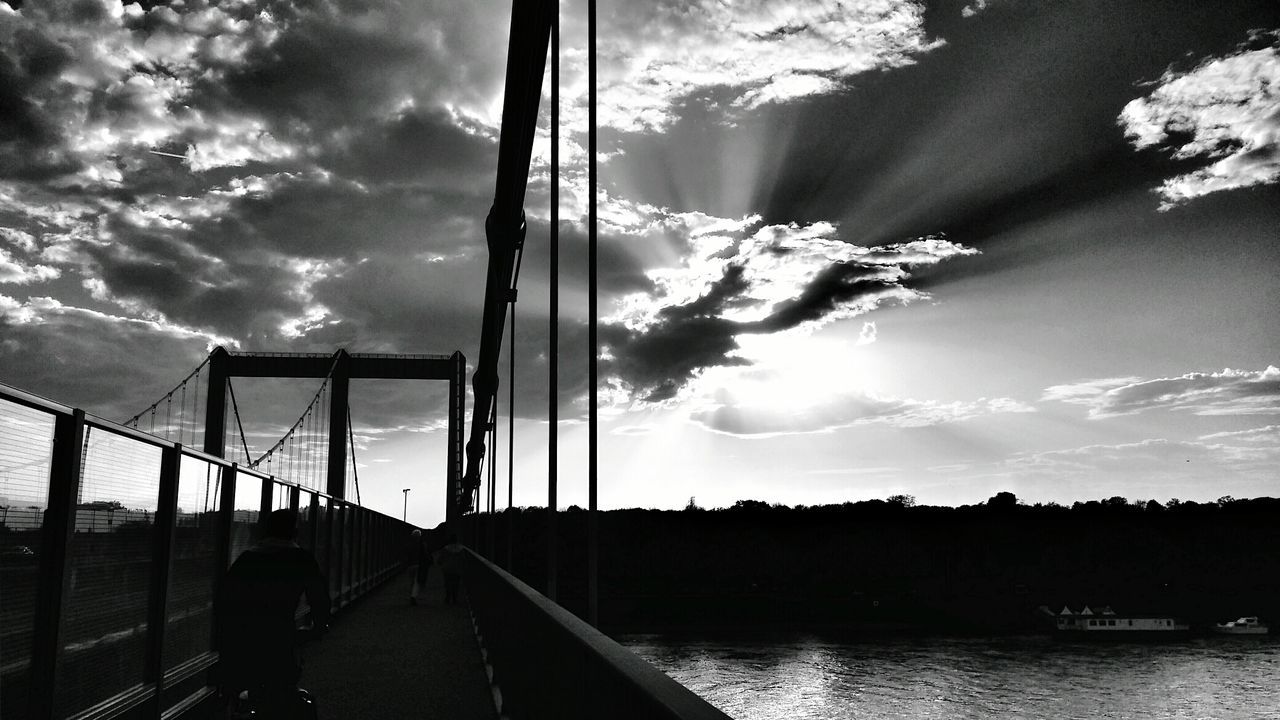 Silhouette cologne rodenkirchen bridge over river against cloudy sky at dusk