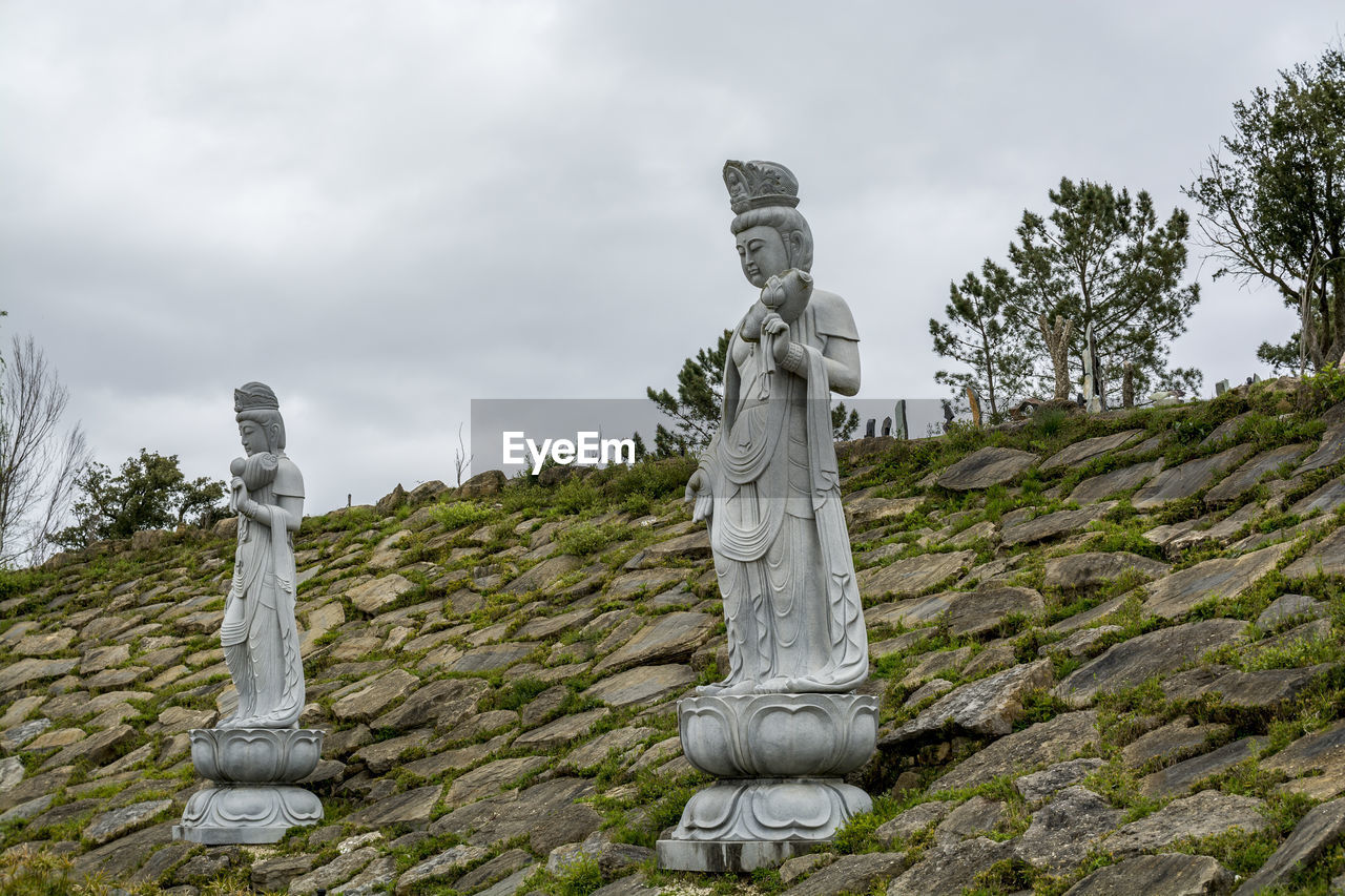 Low angle view of male statues at bacalhoa buddha eden against sky