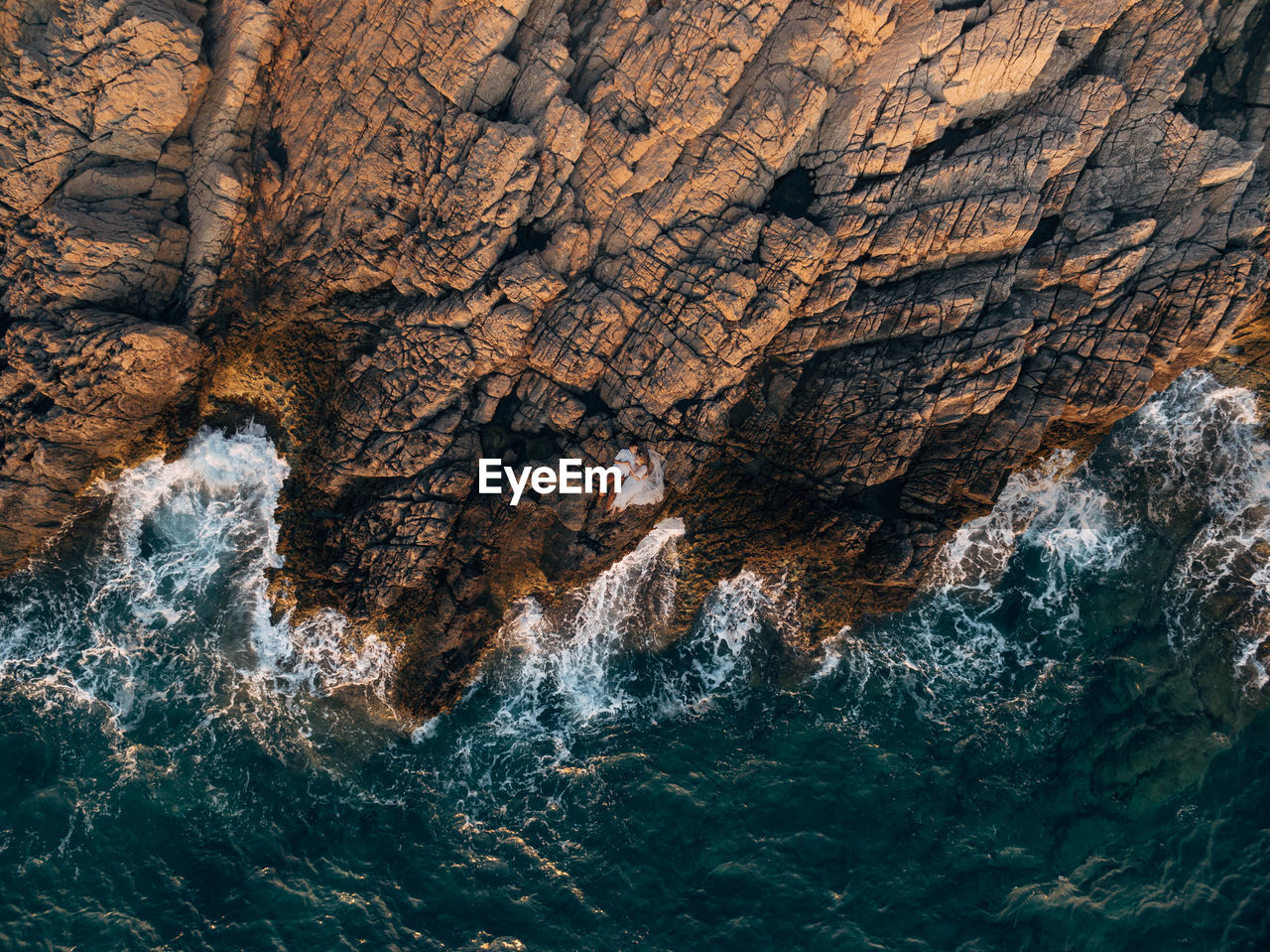 Aerial view of couple lying on rock by sea