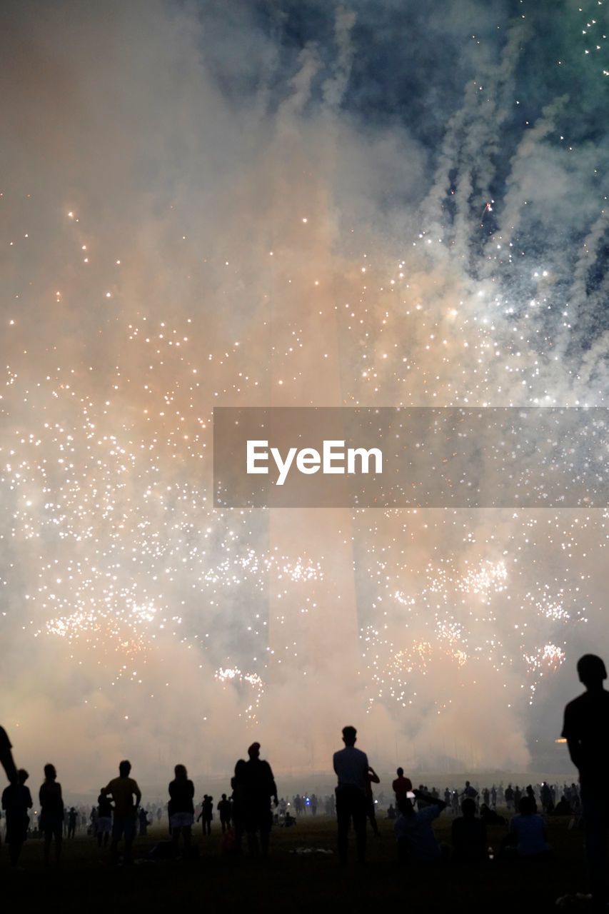 Smoke and firework explosion in fromn of washington monument, usa and silhouettes of spectators