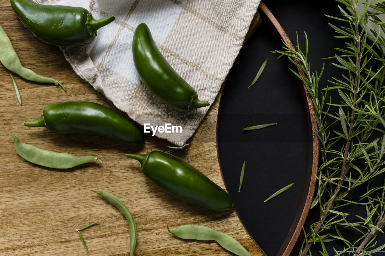 Jalepenos and rosemary on a cutting board flatlay