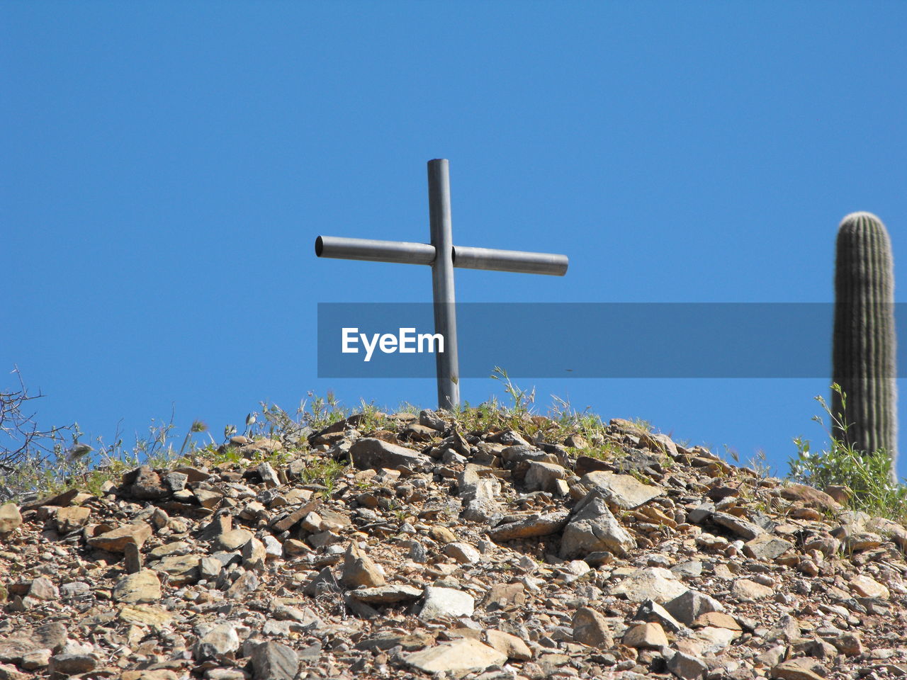 cross, religion, sky, blue, belief, clear sky, spirituality, nature, no people, catholicism, stone, day, sunny, cross shape, grave, symbol, place of worship, sunlight, outdoors, architecture, low angle view, copy space, rock, cemetery