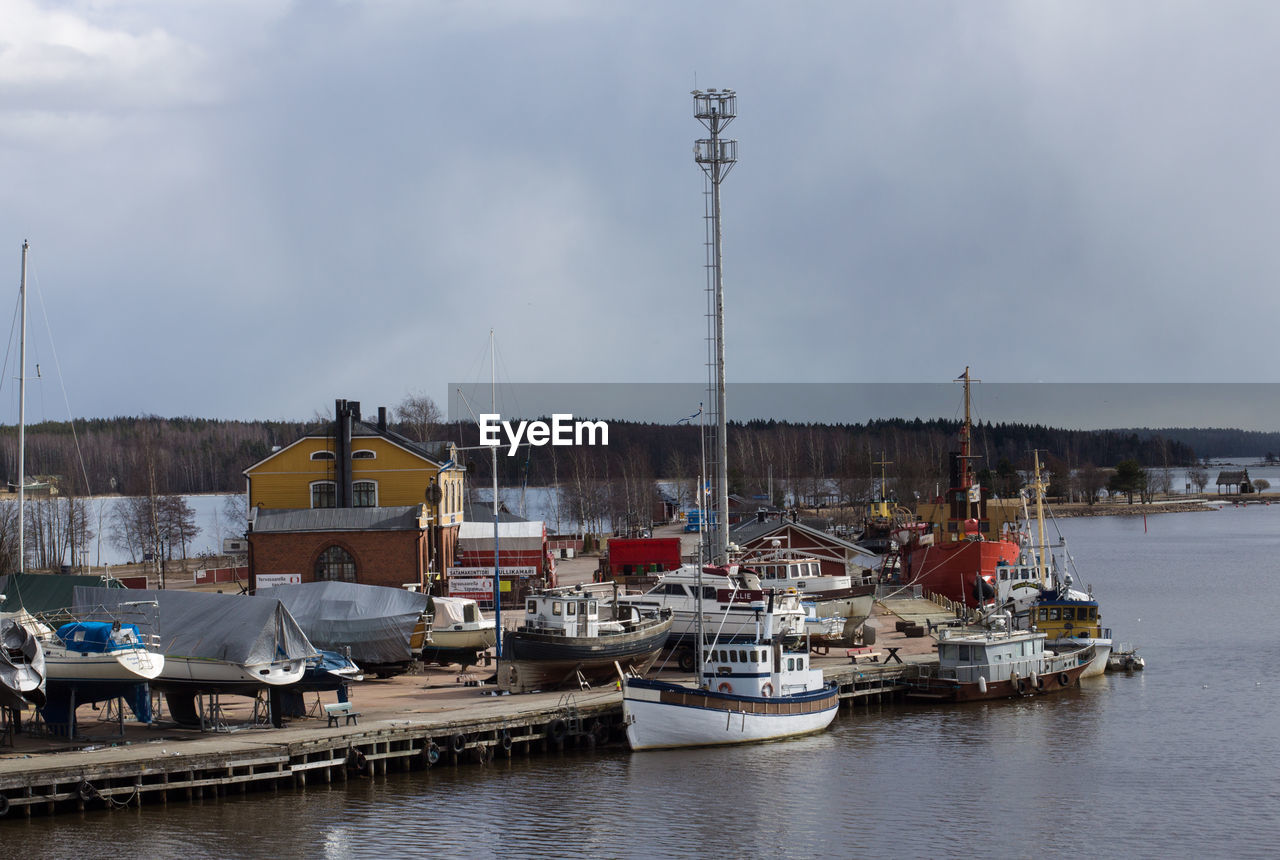 Sailboats moored on harbor against sky