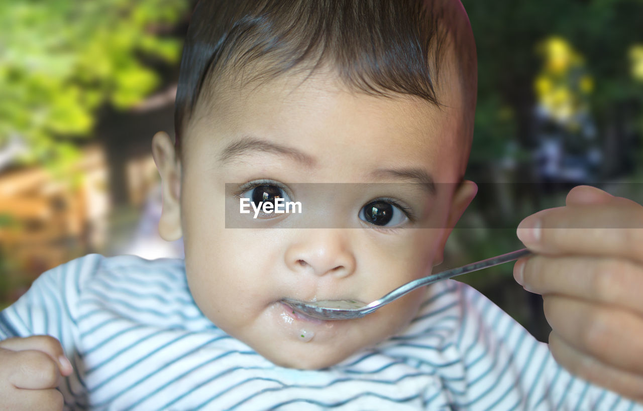 Cropped hand of mother feeding food to cute son 