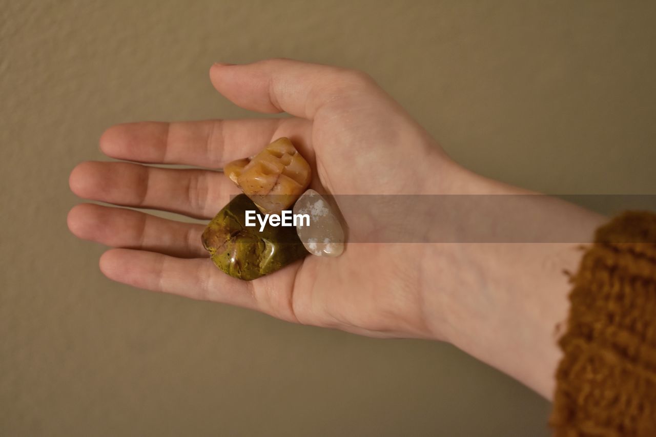 cropped hand of woman holding pills against wall