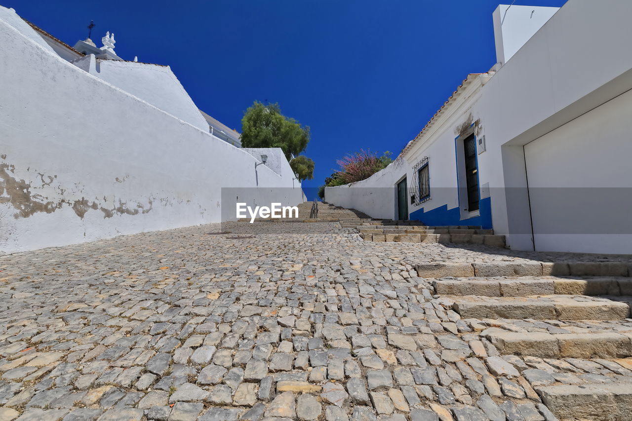 architecture, wall, built structure, sky, building exterior, nature, building, blue, day, clear sky, outdoors, house, travel, travel destinations, city, one person, footpath, tourism